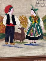 Close-up detail showing the man and woman in traditional folk dress with the goat, fabric textures visible.