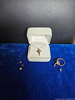 Full lot arranged on blue velvet showing necklace in box, ring, earring, backs