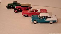 Four model cars aligned side view showing various colors and styles including green truck, red convertible and two sedans.