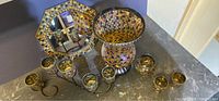 Set of Partylite Global Fusion mosaic glass candle holders arranged on a countertop including a large vase, octagonal mirror tray, several votive holders on metal stand, and loose pieces.
