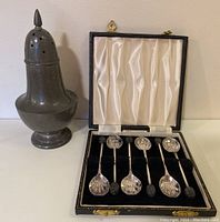 Full view of Civic Pewter sugar shaker and open case of silver plated coffee spoons with coffee bean handles.