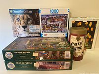 Six assembled photo showing six puzzles including Smithsonian cheetah puzzle, Winter Wonderland, Cobble Hill puzzles, cheese & wine puzzle canister, and New York City puzzle box