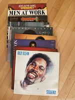 Stack of vintage vinyl record albums with Billy Ocean's 'Suddenly' on top and Kool & The Gang's 'Emergency' peeking at the back.