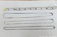 Three silver chains laid out alongside a ruler showing lengths around 8-9 inches.