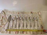 All nine flatware pieces laid out on cloth to show full lot and storage case.