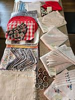 Photo showing various table linens including napkins, placemats, tablecloths, and napkin rings arranged on kitchen counter.