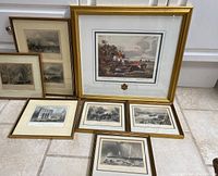 Seven framed vintage historic art prints arranged on floor, mix of color and monochrome prints in various gold and wooden frames.