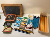 Overview of vintage stationery items laid out on table including chalkboard, crayons, pen nibs, stickers, and pencils