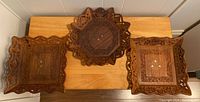 Top view of three carved wooden trays arranged on table showing different shapes and carved details
