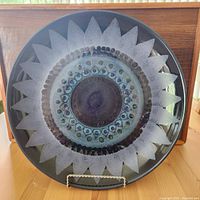 Top view of platter showing decorative concentric circle pattern and spiked border in purple and blue tones.