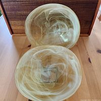 Photo showing two heavy art glass bowls from above, highlighting the swirled cream and amber design and square shape.