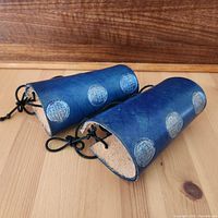 Pair of blue leather artisan bracers showing embossed circular pattern and side profile