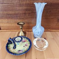 Lot showing all four items: ceramic Japanese candle holder with floral decoration and blue scalloped rim with handle, small brass candle holder, crystal tealight holder by Oleg Cassini, and tall white and blue swirl vintage glass bud vase.