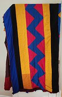 Full view of quilt showing vertical stripes of bold colors (blue, yellow, black) and zigzag pattern in pink and blue