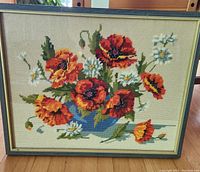 Front view of large framed vintage needlework showing detailed floral embroidery of poppies and daisies in blue vase with clear condition and frame details.