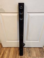 Front view of the tall, slim LG sound bar showing three speaker drivers vertically aligned.