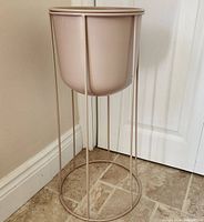 Full view of new metal planter pot on metal stand with round base and vertical supports.