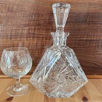 Clear view of Polonia pinwheel crystal decanter and matching crystal glass on wood surface