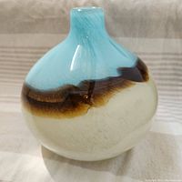 Photo of swirled glass vase showing light blue top, brown swirl midsection, and white bottom.