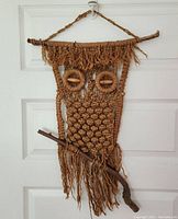 Full view of the vintage macrame owl wall hanging showing overall design and hanging method on wood branch.