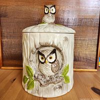 Front view showing the owl cookie jar with owl inside the tree trunk and the owl topper on the lid