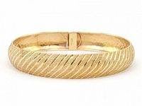 Front view of gold bangle bracelet showing diagonal textured finish and clasp