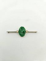 Front view of brooch on white background showing central carved jade flanked by pearls on a white gold bar.