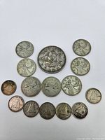 All silver coins laid out on white background, one large dollar at center surrounded by quarters and dimes