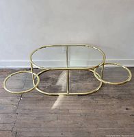 Front view showing brass frame and oval glass top with swing-out trays tucked in