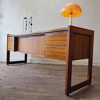 Angled front-left three-quarter view of credenza showing sliding doors, drawers, and open base.