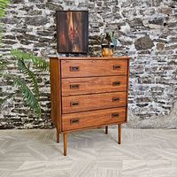 Front view of four-drawer teak dresser against stone wall