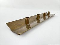 Angled front view showing five cylindrical candle sockets on linear brass base with patina