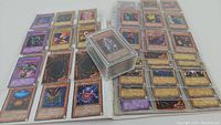 Binder pages laid open showing multiple Yu-Gi-Oh cards and a clear plastic deck box in center