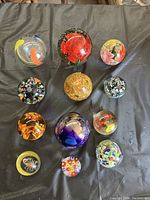 Top view of all 12 paperweights showing various colors, patterns, and sizes.