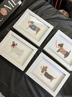 Overview of all four framed cartoon dog illustrations placed on a table showing front view.