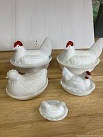 Front view of all five milk glass chicken dishes with details on lids and bases visible