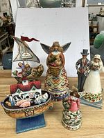 Five Jim Shore figurines shown together including a Noah's Ark, an angel, a bride and groom couple, and a small angel figurine.