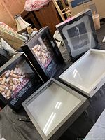 Photo showing all five shadowbox frames on a table, three brand new in packaging and two used frames open with hinged glass front.