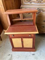 Front view of mini cabinet showing drawer, two doors with lighter wood panels, and cubby storage on top
