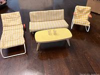 Miniature patio furniture set consisting of lounge chair, couch, armchair with yellow checkered fabric covers and yellow coffee table with two small clear glasses.