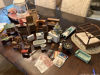 Overview photo showing all dollhouse furniture pieces arranged on a table including chairs, bed, tables, bathtub, toilet, piano, and various smaller items