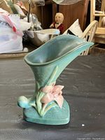 Green Roseville ceramic vase with pink flower decoration, showing full profile of vase with flared rim and rounded base.
