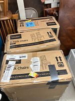 Photo showing three cardboard boxes, each labeled as containing two Better Homes & Gardens Maddox Crossing 2-pack dining chairs, white color.