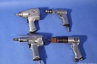 Four pneumatic air tools against blue background, showing two impact wrenches, one air drill, and one air chisel
