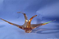Angled side view showing amber glass with three upward wing shapes and reflective surface.
