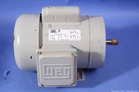 Photo of gray sealed electric motor showing the full housing, shaft, and terminal box cover with WEG logo.