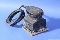 Black & Decker 7443-04 1/4 sheet finishing palm sander with power cord coiled and tied, showing sawdust dust buildup on black plastic and metal parts