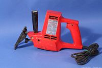 Red Wen Model 1600 reciprocating saw showing left side with label, handle attached vertically, power cord coiled.
