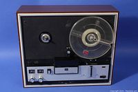 Front view of Toshiba PT-850S reel-to-reel tape deck with wood grain casing and one clear plastic reel on the right side, various control switches and knobs on front panel.