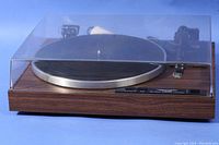 Front view of Realistic LAB-290 turntable with clear plastic dust cover in place, showing wood grain base and metal platter.